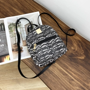 Detail of mini backpack with black and white woven pattern and gold-tone metal zippers