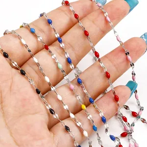 Colorful enamel teardrop charms on a silver stainless steel necklace chain held by hand