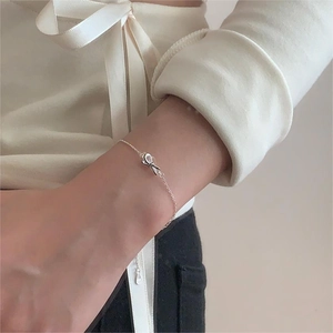 Close-up of S925 sterling silver bow charm bracelet worn on a woman's wrist