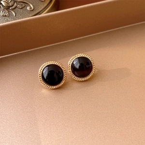 Close-up of vintage gold earrings with large round black cabochon gems on a tray