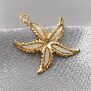 Detailed macro view of a golden starfish pendant with iridescent shell inlays on silk