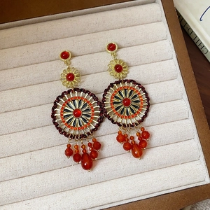 Macro detail of ethnic silver needle earrings with agate beads and red stone pendant