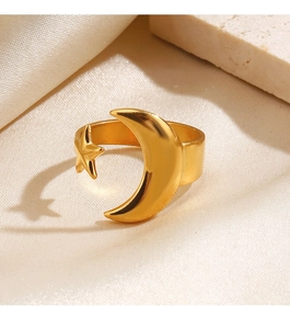 Detail of adjustable gold moon and star ring on cream silk and stone background