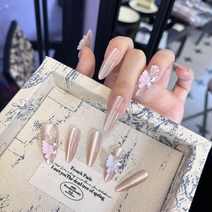 Dettaglio unghie a pressione rosa cat-eye con farfalle 3D, perle e strass su vassoio decorato
