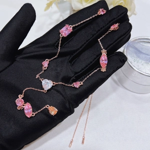 Close-up of rose gold necklace with pink and yellow crystal gems on black satin