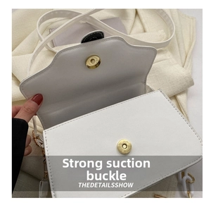 Detail of the white PU leather handbag with a gold magnetic snap and acrylic chain strap