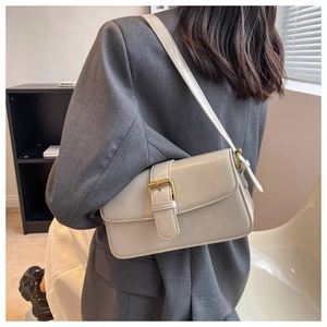 Side view of cream rectangular leather crossbody bag with vintage gold buckle on model