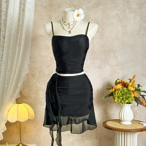 Detail of black camisole set with ruffled mini skirt and mesh trim on model stand