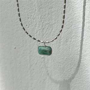 Detail of a rectangular green stone pendant with a silver-tone olive bead chain necklace