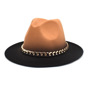 Détail d'un chapeau fedora bicolore avec couronne camel, bord noir et chaîne dorée