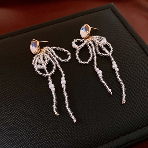 Detail showing the intricate bow shape and flowing pearl tassels on gold plated earring