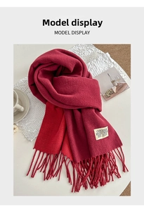 Detailed close-up of dark red cashmere-like scarf featuring soft fringe and brand label