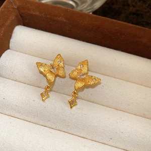 Macro view of gold plated matte butterfly earrings with zircons in a jewelry box