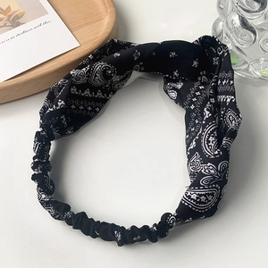 Detail of vintage paisley printed headband with a decorative top knot on white table