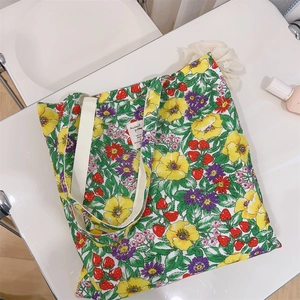 Vista piatta della borsa in cotone con stampa di fragole e fiori e manico in tessuto