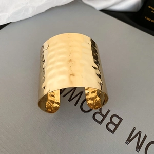 Macro shot showing the hammered texture and golden finish on the irregular metal cuff bracelet