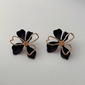 Detail of hollow floral earrings with black matte petals and gold metal wire finish