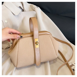 Detail of khaki suede handbag with golden metal twist lock on beige trench coat