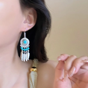 Detail of dreamcatcher earrings with turquoise beads and silver-toned hanging feathers