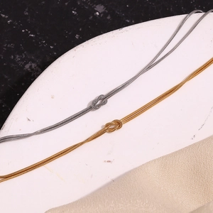 Detail of 18K gold and silver snake chain bracelets with minimalist knot design