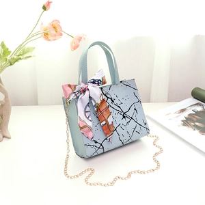 Close-up of light blue marble handbag featuring gold chain strap and floral silk scarf