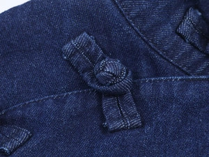 Detailed macro view of dark blue denim fabric with traditional Chinese knot buttons