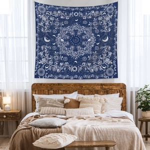 Detail of bohemian sun and moon tapestry on a dark blue background in a cozy bedroom