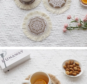 Close-up of a round jute placemat with beige fringe and white lace pattern for home decor