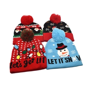 Flat lay detail of four festive Christmas knit beanies with pom-poms and holiday patterns