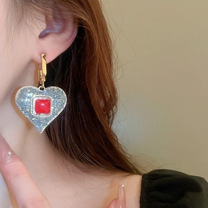Close-up of retro heart earring with red square crystal on a female model