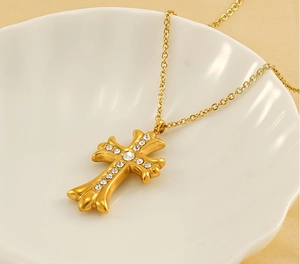 Close-up of gold-plated cross pendant with white zircon insets on shell textured tray