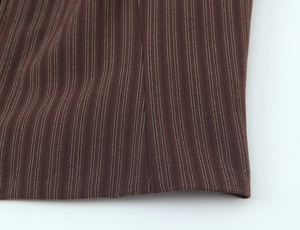 Close-up of brown pinstripe fabric texture and fine stitching detail on a women's set