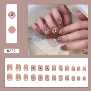 Kurze runde Kunstnägel in Nude-Rosa mit Kamelienblüten und silbernem Glitzerrand