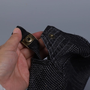 Close-up of metal snap-button adjustment strap on plaid denim flat cap.