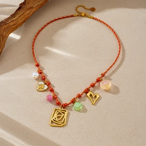 Collier en corde rouge tressée avec pendentifs dorés et perles colorées sur bois