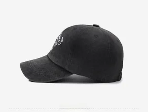 Close-up of white script embroidery on a dark grey washed wool baseball cap