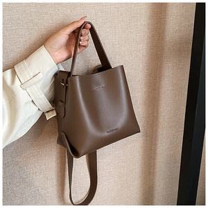 Detail view of deep brown leather bucket bag with top handle and adjustable strap