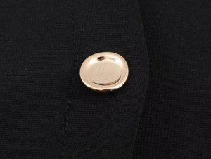Macro detail of elegant gold mirror buttons on a high-quality black knitted dress fabric