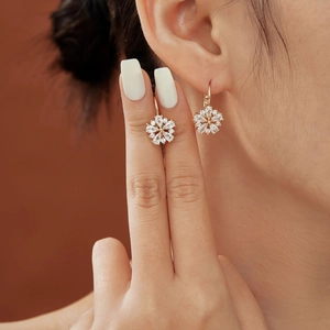 Elegant rose gold floral earrings featuring shimmering crystals on a model's ear