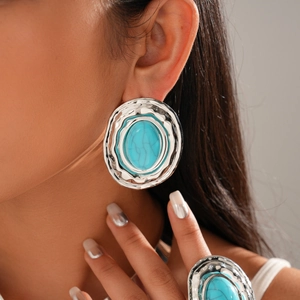 Detailed view of irregular silver textured earrings and ring with turquoise stone inlay
