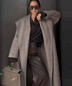 Detailed view of women's long grey camel hair coat with belted waist and matching handbag
