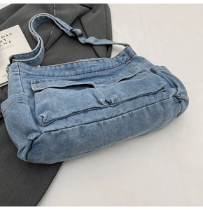 Detail view of denim crossbody bag featuring dual front pockets and adjustable shoulder strap