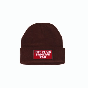 Macro shot of embroidered 'PUT IT ON SANTA'S TAB' red patch on a brown knit beanie