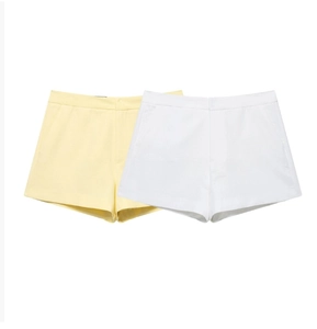 Detailed view of high-waist cotton blend shorts in pale yellow and white with side pockets