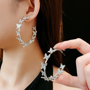 Détail de créoles papillon argentées avec strass scintillants portées par un mannequin