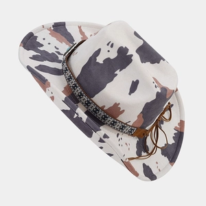 Detail of cow print western hat featuring ethnic geometric band and leather tassel ties