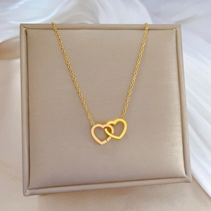 Detailed view of interconnected golden double heart necklace on silk and beige tray