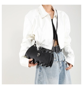 Chic black bat-shaped crossbody bag with silver skull detail worn by a model