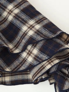 Detailed close-up of plaid fabric with dark blue, brown and cream stitching texture