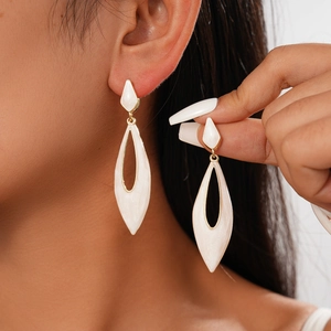 Detail of white drop-shaped hollow earrings with gold borders on a model
